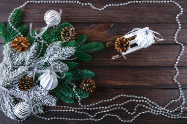 Noel arkaplanı beyaz Noel topları, dekoratif kızak, gümüş çelenk ve çam kozalakları, üst manzara. Şenlikli kış kompozisyonu