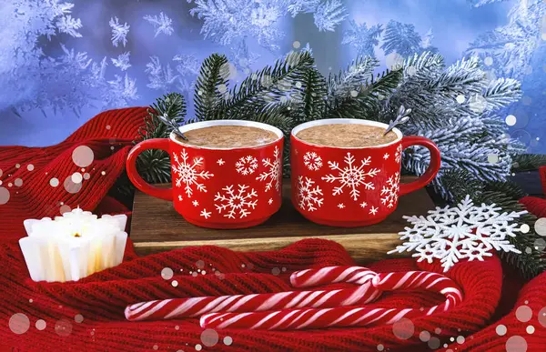 Christmas composition with two red coffee cups, snowflakes, lollipops, burning white candle, Christmas tree branches, red scarf on snowy background.