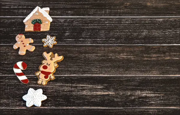 Christmas gingerbread, deer, gingerbread man, house, lollipop, snowflakes on dark wooden background. Winter Christmas background with gingerbread.