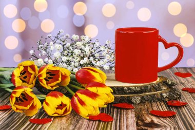 Kalpli kırmızı bir fincan kahve, bir buket lale ve bokeh etkisindeki çingene çiçeği. Sevgililer günün kutlu olsun.