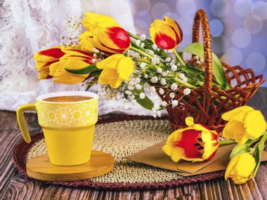 Romantik bahar hala hayattadır. Sepette bir buket kırmızı ve sarı lale, çingene çiçekleri, sarı bir fincan kahve, el işi zarfları.