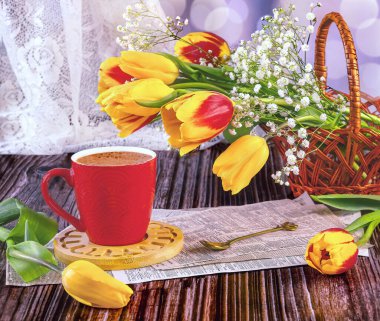 Bahar hala hayattır. Sepette bir buket kırmızı ve sarı lale, çingene çiçekleri, kraft kağıdında kırmızı bir fincan kahve..