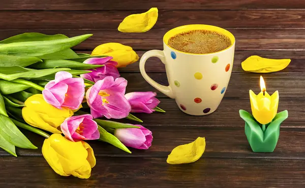 Bahar, beyaz bir benekli kahve, bir buket sarı ve pembe lale çiçekleri ve ahşap arka planda bir mum ile durgun bir hayattır..