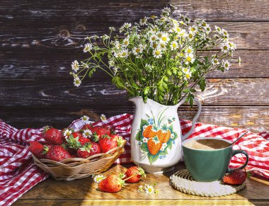 Bir buket papatya çiçeği, çilekli bir sürahi, taze çilekli bir sepet, yeşil bir fincan kahve. Vahşi çiçeklerle dolu bir yaz