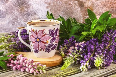 Çiçekli klasik mor kahve ve masanın üzerinde mor ve pembe lupin çiçekleri. Çiçeklerle dolu yaz
