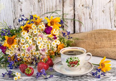 Bir fincan çilekli kahve, masada olgun çilek hasadı, ahşap arka planda bir fincan kahve..