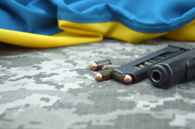 Askeri kamuflaj pikselinin ve Ukrayna bayrağının arka planında fişekleri olan bir Makarov tabancası. Başbakan daha kısa. Ukrayna 'da Savaş.