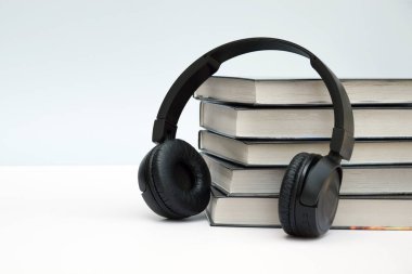 Açık arkaplanlı siyah kulaklıklar. Ses kitapları veya modern eğitim kavramı.