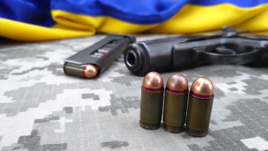 Kharkiv, Ukrayna - 18 Ekim 2022: Askeri kamuflaj pikseli ve Ukrayna bayrağının arka planında kartuşlar bulunan bir Makarov tabancası. Başbakan daha kısa. Ukrayna 'da Savaş.