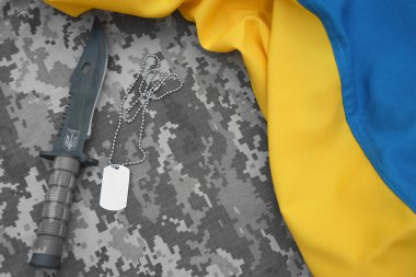 Askeri bıçak ve piksel kamuflaj arka planında mızrak olan bir künye. Ukrayna 'da Savaş.