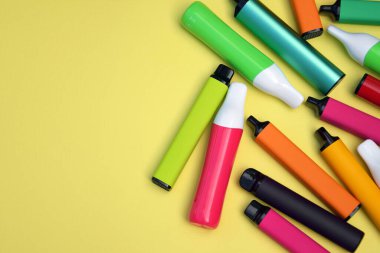 Parlak sarı arka planda tek kullanımlık elektronik sigara seti. Modern sigara, buhar ve nikotin konsepti.