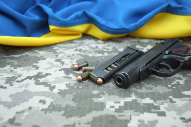 Askeri kamuflaj pikselinin ve Ukrayna bayrağının arka planında fişekleri olan bir Makarov tabancası. Başbakan daha kısa. Ukrayna 'da Savaş.