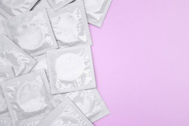 Pembe arka planda bir sürü açılmamış prezervatif paketi var. Hamilelik veya cinsel yolla bulaşan hastalıkları azaltmak için prezervatif kullanmak. Cinsel yolla bulaşan hastalıklar. Güvenli seks ve üreme sağlığı kavramı.