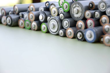 Kullanılmış AA bataryalar ve çevresel atık ve yeşil arka planda toprak toksik bataryalar. Zararlı ve geri dönüşümlü nesnelerin işlenmesi kavramı.