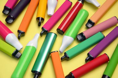 Parlak sarı arka planda tek kullanımlık elektronik sigara seti. Modern sigara, buhar ve nikotin konsepti.