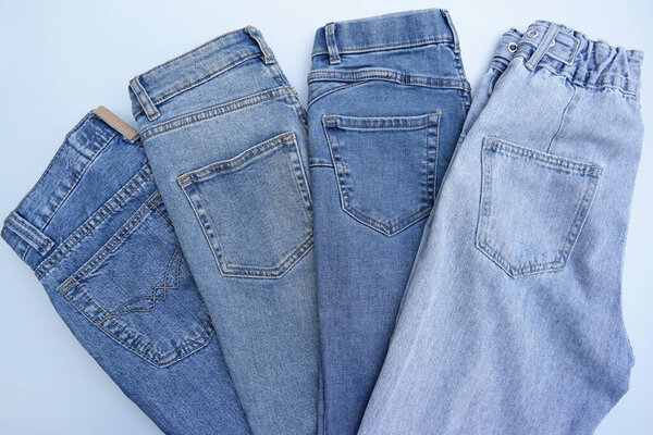 Lots of jeans pants in a stack. Denim background. The concept of buying, selling, shopping and trendy modern clothes.