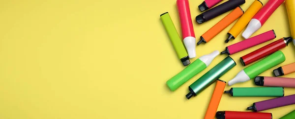 stock image Set of multicolor disposable electronic cigarettes on a bright yellow background. The concept of modern smoking, vaping and nicotine.