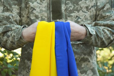 Ukraynalı bir asker, ulusal bayrağı güçlü bir sembolün sembolü olarak elinde tutuyor. Ukrayna 'da savaş. Kazaklar Günü ve Ukrayna 'nın Savunucusu.