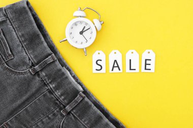 Düz yatış, siyah kot, beyaz etiketler ve sarı arka planda indirim. Alışveriş ve indirim konsepti. Kara Cuma.