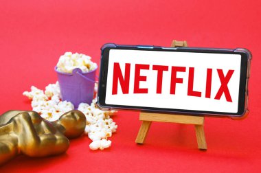 KHARKIV, UKRAINE - 1 Haziran 2020: Netflix stüdyo logosu, Oscar figürü ve patlamış mısırlı akıllı telefon. Film endüstrisi kavramı.