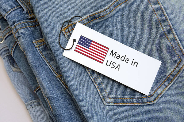 Синие джинсы, белая этикетка и лейбл Made in USA. Концепция покупки, продажи, шопинга и трикотажной современной одежды.