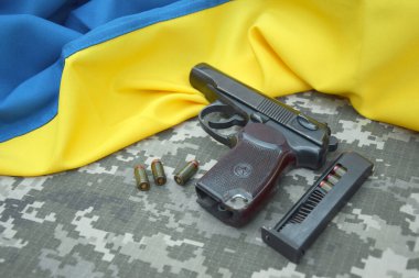 Askeri kamuflaj pikselinin ve Ukrayna bayrağının arka planında fişekleri olan bir Makarov tabancası. Başbakan daha kısa. Ukrayna 'da Savaş.