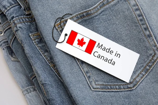 Detail of blue jeans, white label and Made in Canada lettering. The concept of buying, selling, shopping and trendy modern clothes.