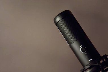 Studio condenser microphone isolated on dark background. The concept of vocals, streaming, podcast. Space for text.