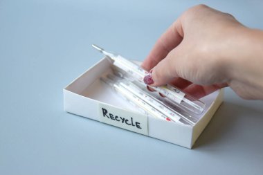 Eski civa termometreleri ve çevresel ve toprak toksik maddelerin mavi arka planda düzgün bir şekilde imha edilmesi. Zararlı ve geri dönüşümlü nesnelerin işlenmesi kavramı.