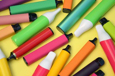 Parlak sarı arka planda tek kullanımlık elektronik sigara seti. Modern sigara, buhar ve nikotin konsepti.