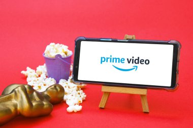 KHARKIV, UKRAINE - 1 Haziran 2020: Prime video stüdyo logosuna sahip akıllı telefon, Oscar figürü ve patlamış mısır. Film endüstrisi kavramı.