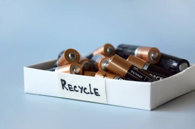 KHARKIV, UKRAINE - 22 Şubat 2022: Kullanılmış AA bataryalar ve çevresel ve toprak zehirli bataryaların mavi arka planda düzgün bir şekilde imha edilmesi. Zararlı ve geri dönüşümlü nesnelerin işlenmesi kavramı.