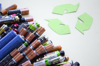 KHARKIV, UKRAINE - 11 Haziran 2022: Kullanılmış AA bataryalar ve yeşil zemin üzerinde çevresel ve toprak toksik bataryaların uygun şekilde imha edilmesi. Zararlı ve geri dönüşümlü nesnelerin işlenmesi kavramı.