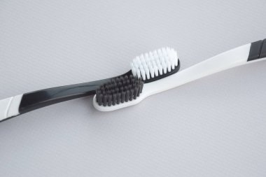 Toothbrushes with a small figure of a tooth on a light background. Dental health concept.