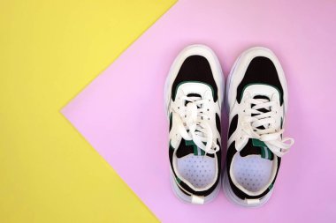 Bright female sneakers on pink-yellow background. Fashion blog or magazine concept. Flat lay top view copy space minimal background.