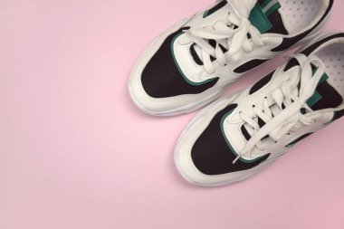 Bright female sneakers on light pink background. Fashion blog or magazine concept. Flat lay top view copy space minimal background.