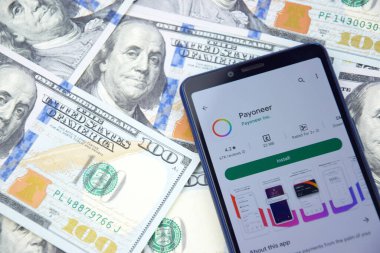 Kharkiv, Ukrayna - 13 Mart 2023: Akıllı telefon ekranında Paeveryone mobil bankacılık uygulaması. Amerikan dolar banknotlarının arka planı.
