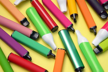 Parlak sarı arka planda tek kullanımlık elektronik sigara seti. Modern sigara, buhar ve nikotin konsepti.