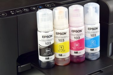 KHARKIV, UKRAINE - FEBRUARY 11, 2023: Four bottles of ink Epson, yellow, red, blue, black, built-in to the Epson L3150 series printer.