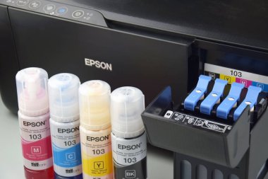 KHARKIV, UKRAINE - FEBRUARY 11, 2023: Four bottles of ink Epson, yellow, red, blue, black, built-in to the Epson L3150 series printer.