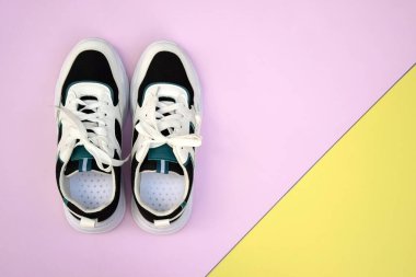 Bright female sneakers on pink-yellow background. Fashion blog or magazine concept. Flat lay top view copy space minimal background.