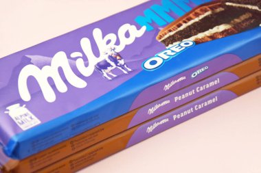 KHARKIV, UKRAINE - 12 Şubat 2023: Oreo aromalı çikolatalı Milka ve yumuşak pembe arkaplanda karamel.