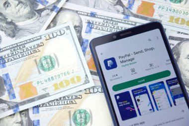 Kharkiv, Ukrayna - 13 Mart 2023: PayPal mobil bankacılık uygulaması akıllı telefon ekranında. Amerikan dolar banknotlarının arka planı.