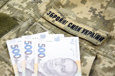 Ukrayna hrivnisi, Ukrayna silahlı kuvvetlerinin yazılı olduğu askeri bir pikselin arka planına karşı. Ücret, ödeme ve orduya bağış kavramı..