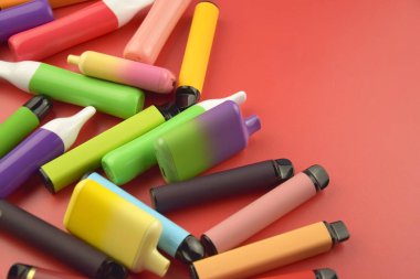 Kırmızı arka planda tek kullanımlık elektronik sigara seti. Modern sigara, buhar ve nikotin konsepti.