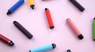 Pembe arka planda tek kullanımlık elektronik sigara seti. Modern sigara, buhar ve nikotin konsepti.