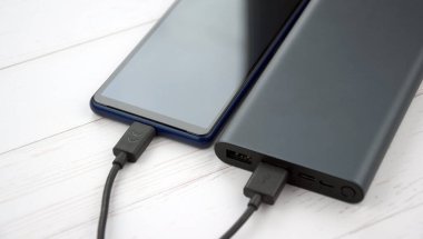 Mobil cihazları şarj etmek için güç bankası. Güç bankası olan siyah akıllı telefon şarj aleti. Mobil aygıtlar için dış pil.