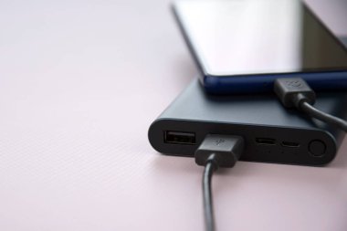Mobil cihazları şarj etmek için güç bankası. Güç bankası olan siyah akıllı telefon şarj aleti. Mobil aygıtlar için dış pil.