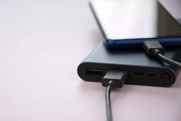 Power bank for charging mobile devices. Black smart phone charger with power bank. External battery for mobile devices.