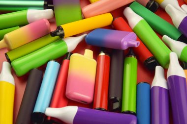 Kırmızı arka planda tek kullanımlık elektronik sigara seti. Modern sigara, buhar ve nikotin konsepti.